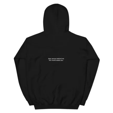 Person wears black hoodie with subtle design, facing away, letters read "Dear Person Behind Me.